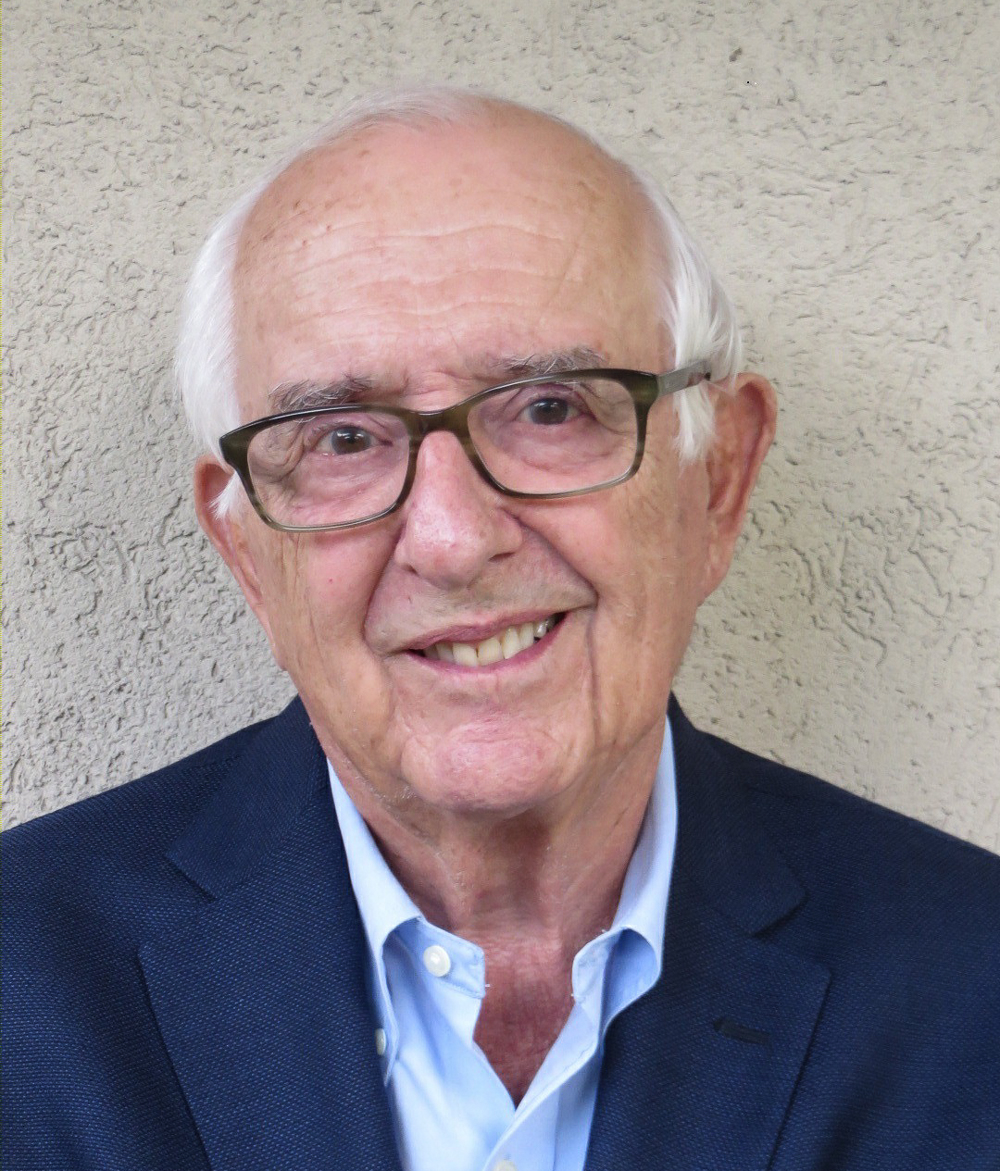 Portrait of Jack Heuer in 2017, smiling, wearing glasses and a navy jacket
