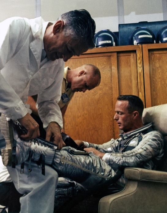 Suit tech Joe Schmitt and astronaut John Glenn work to get Scott Carpenter suited for his May 24, 1962 launch into space.