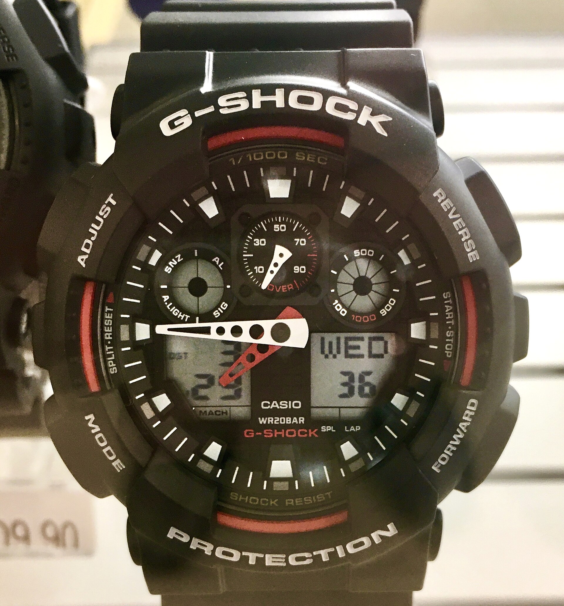 A black and red Casio G-Shock GA-100 analogue-digital watch in a shop display