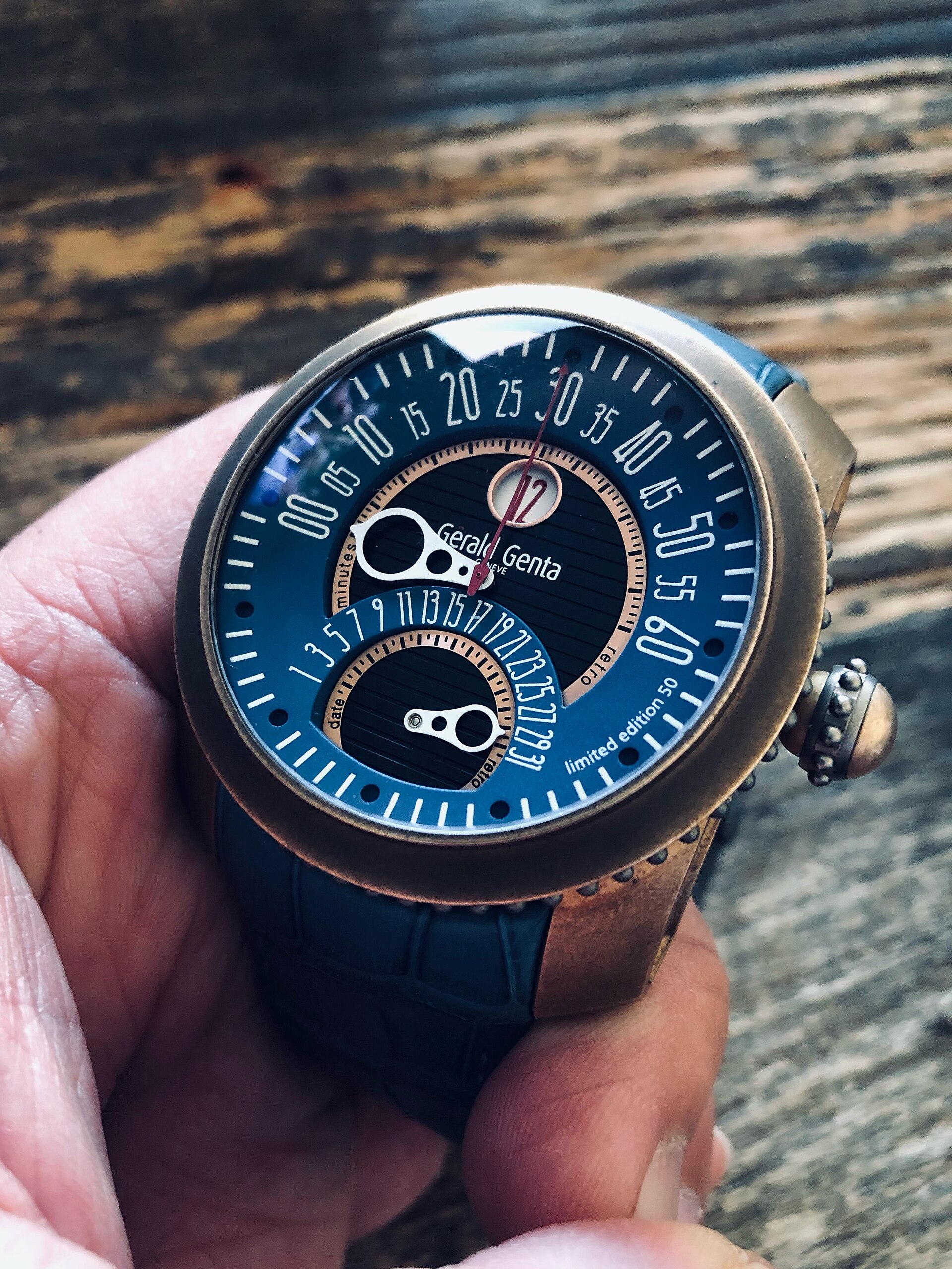 A bronze Gerald Genta Gefica Safari with a blue retrograde dial held in a hand