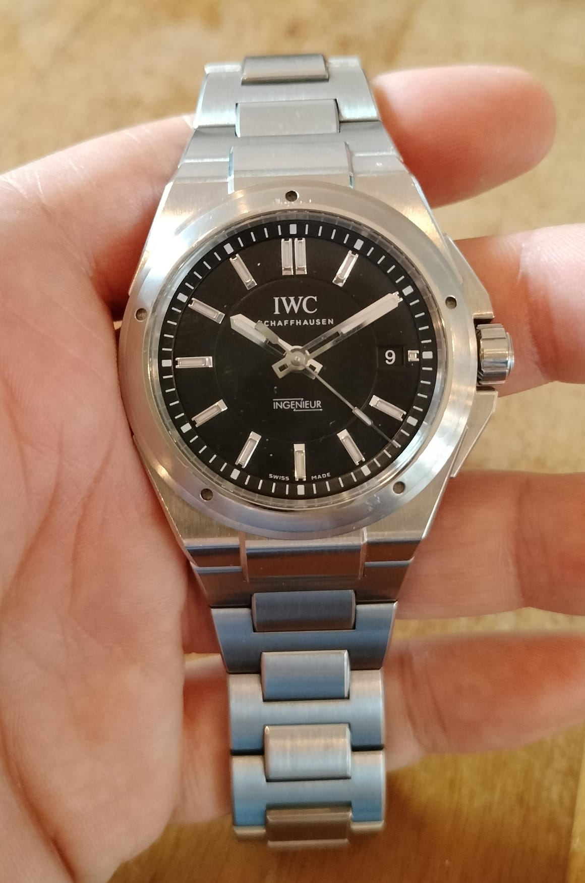 An IWC Ingenieur IW323902 with a black dial and five-screw bezel held in a hand