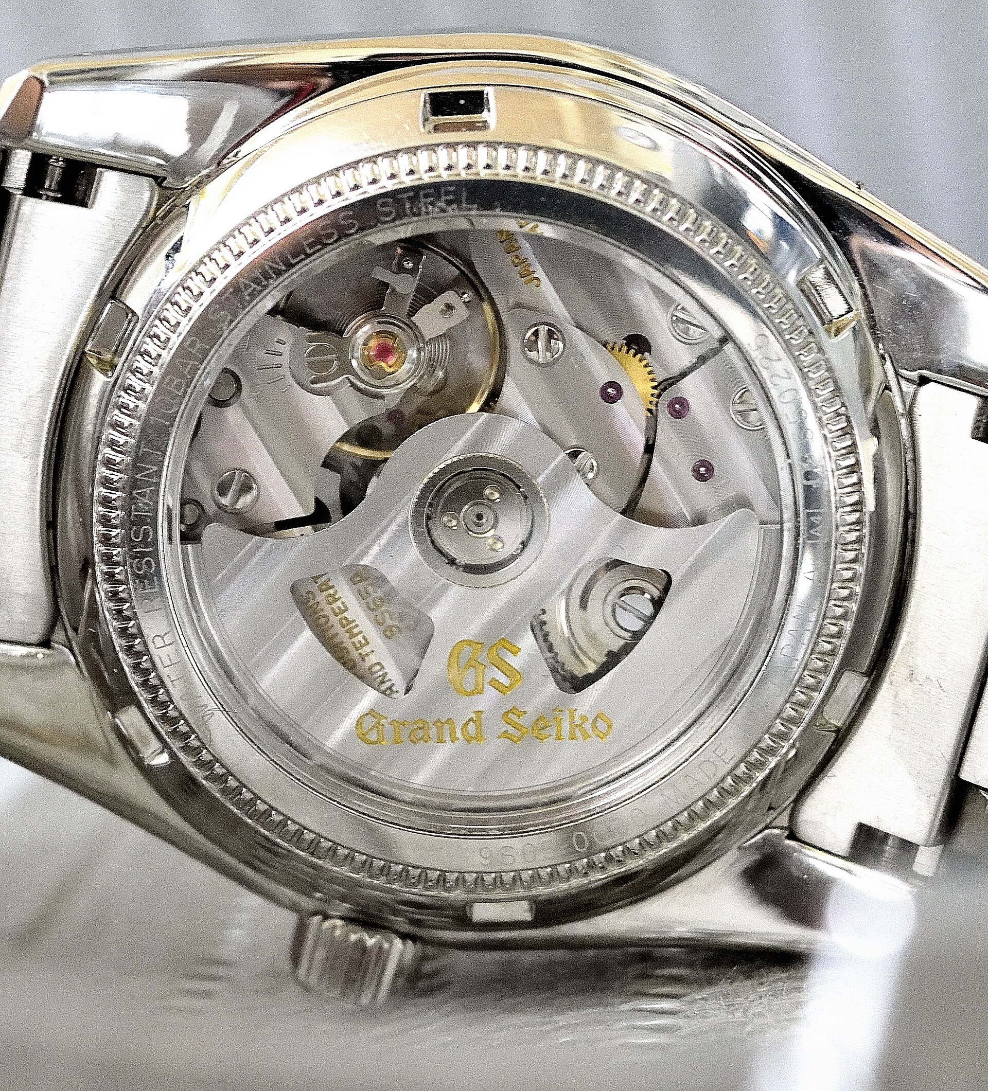 A Grand Seiko calibre 9S65 automatic movement seen through the sapphire case back, with the GS lion on the rotor