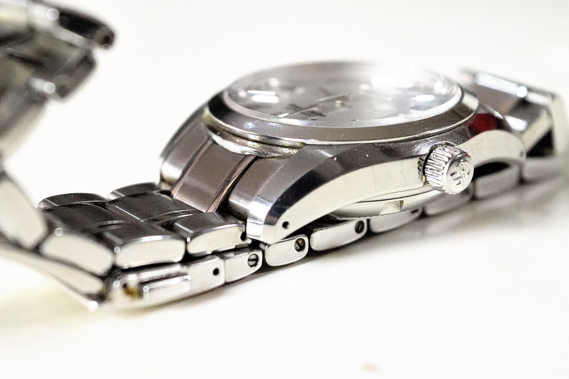 Side view of a steel Grand Seiko case and bracelet showing flat mirror-polished flanks and the crown