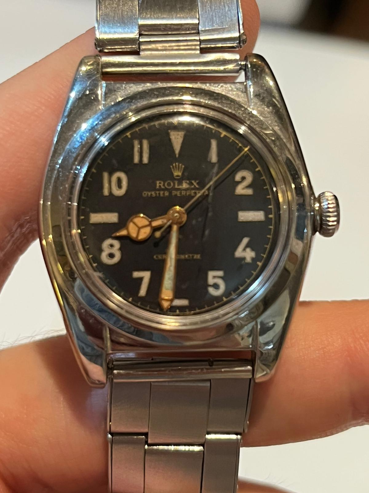 A 1940s Rolex Oyster Perpetual Bubbleback 2940 with a black dial held between two fingers