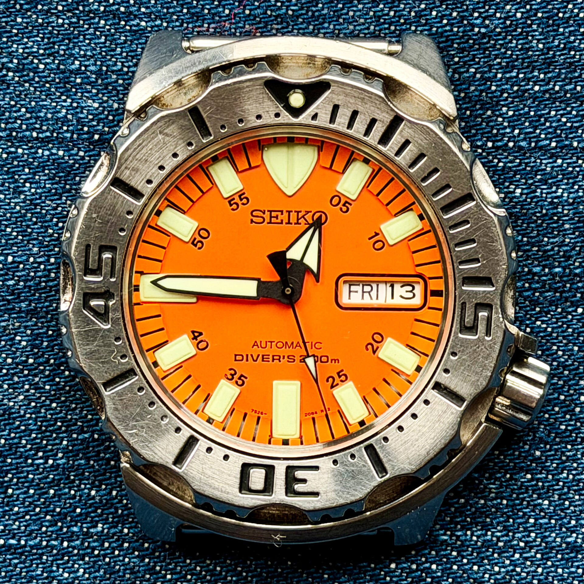A Seiko SKX781 Orange Monster with an orange dial and toothed steel bezel on a denim background