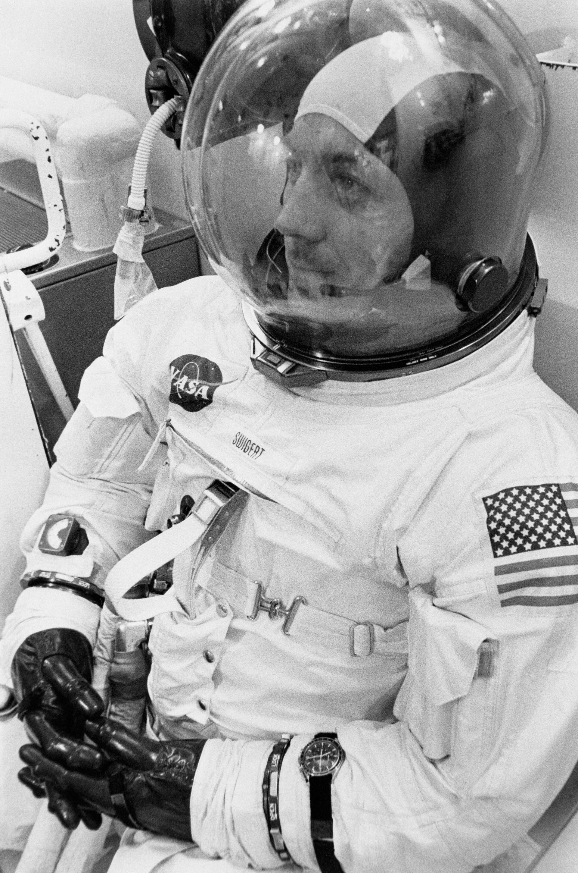 Jack Swigert seated in his Apollo 13 pressure suit and helmet with a wristwatch visible on his left wrist